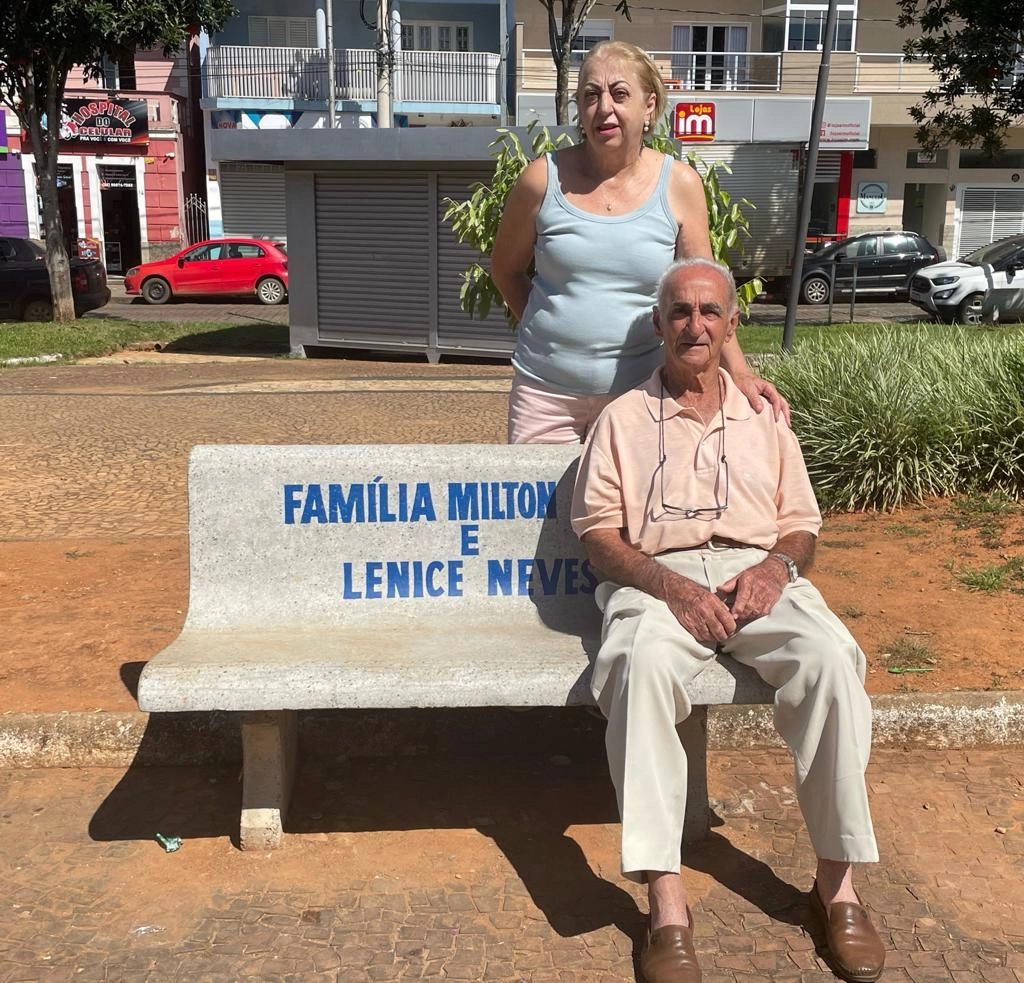 Sandra Magnoni e Hélio Magnoni (o Bibi), cunhada e sogro de Milton Neves no banco em homenagem à família Neves na Praça dos Andradas, em Muzambinho