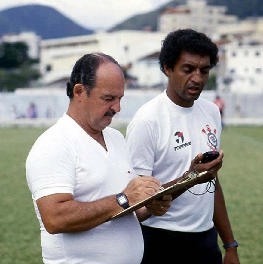 Em 1986, Rubens Minelli, treinador do Corinthians, faz anotações com sua prancheta na mão, ao lado de seu auxiliar, Basilio. Foto: arquivo pessoal de Rubens Minelli