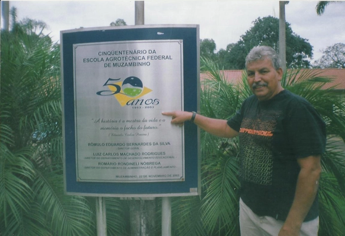 Guilherme ao lado da placa comemorativa dos 50 anos da Escola Agrotécnica Federal de Muzambinho. Foto: arquivo pessoal de Guilherme de Souza